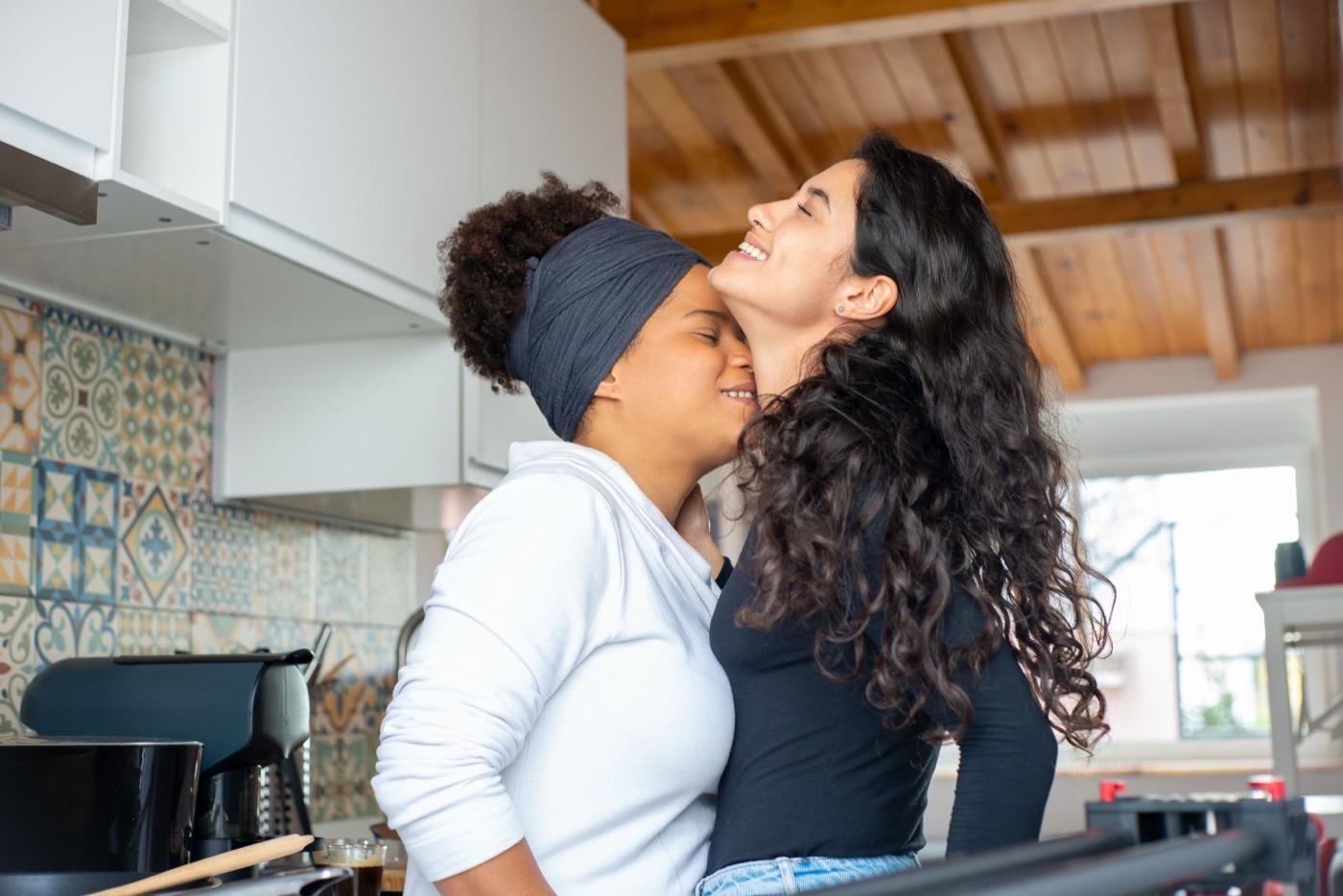 Two women laughing together in a bright kitchen
