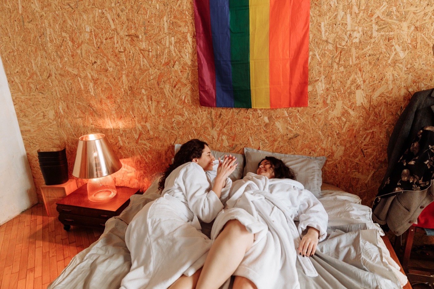 Two women smiling with a Pride flag nearby